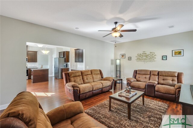 living room with dark wood-type flooring and ceiling fan