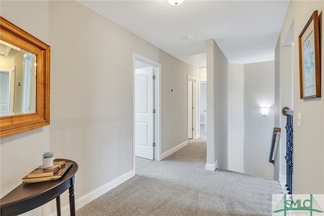 corridor featuring a textured ceiling and light colored carpet