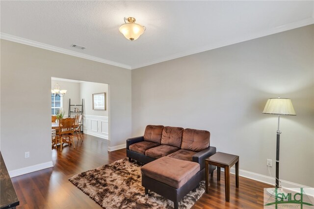 living room featuring dark hardwood / wood-style floors, a textured ceiling, crown molding, and a notable chandelier