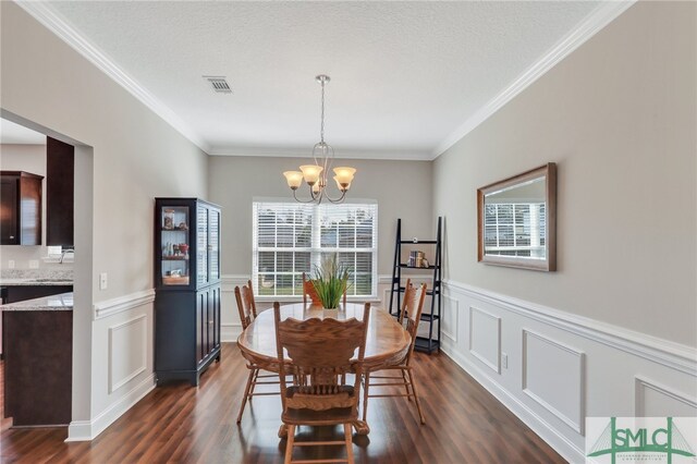 dining space featuring dark hardwood / wood-style flooring, a chandelier, a textured ceiling, and crown molding