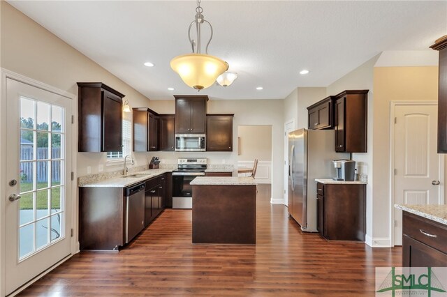 kitchen with stainless steel appliances, sink, decorative light fixtures, a kitchen island, and dark hardwood / wood-style flooring