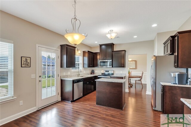 kitchen with stainless steel appliances, sink, dark hardwood / wood-style floors, a center island, and pendant lighting