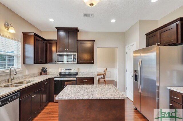 kitchen with hardwood / wood-style flooring, appliances with stainless steel finishes, sink, and a kitchen island