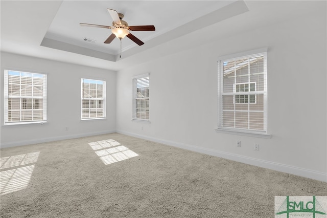 spare room featuring a raised ceiling, ceiling fan, carpet flooring, and crown molding