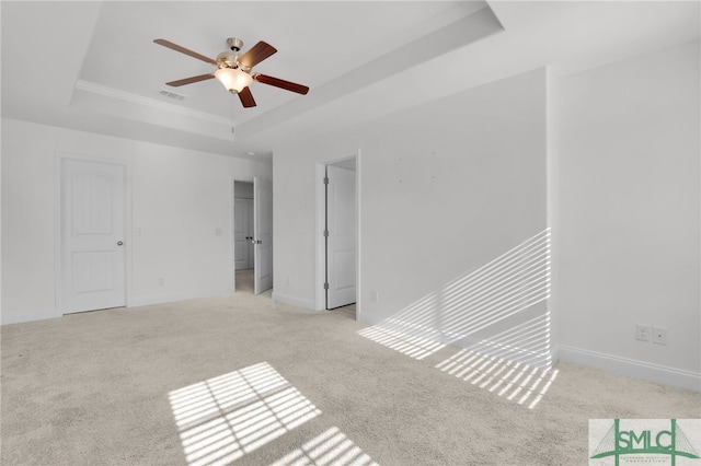 carpeted spare room with a tray ceiling and ceiling fan