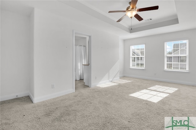 spare room with a tray ceiling, ceiling fan, crown molding, and light colored carpet