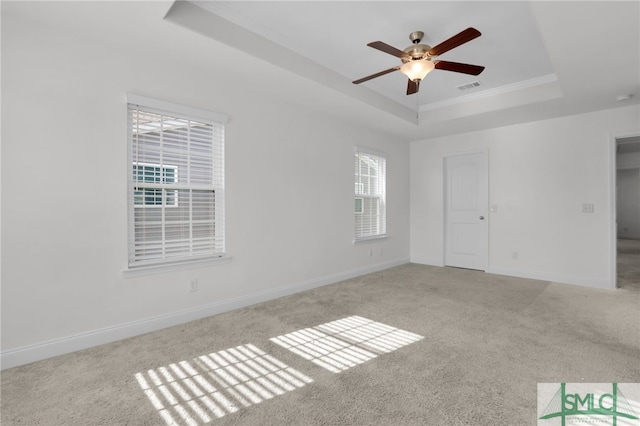 carpeted spare room with ceiling fan, a raised ceiling, and crown molding