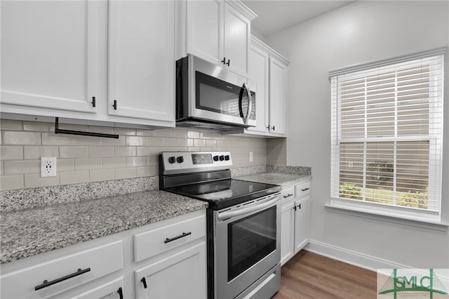 kitchen with stainless steel appliances, light stone counters, dark hardwood / wood-style floors, backsplash, and white cabinets