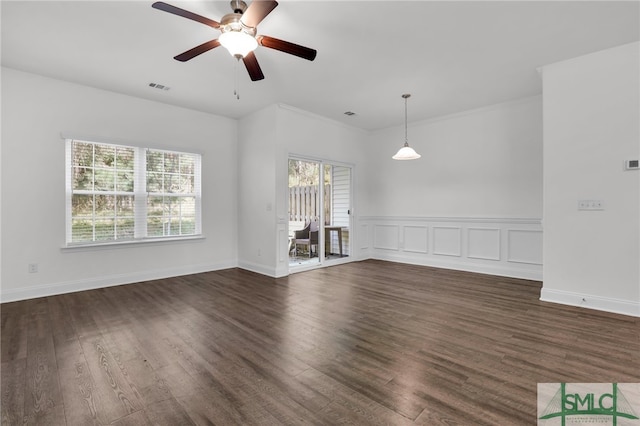 empty room with ceiling fan, dark wood-type flooring, and ornamental molding