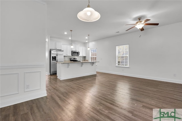 kitchen featuring white cabinets, appliances with stainless steel finishes, hanging light fixtures, and a breakfast bar area