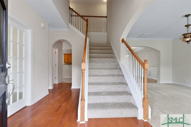 stairs featuring an inviting chandelier, hardwood / wood-style floors, and ornamental molding