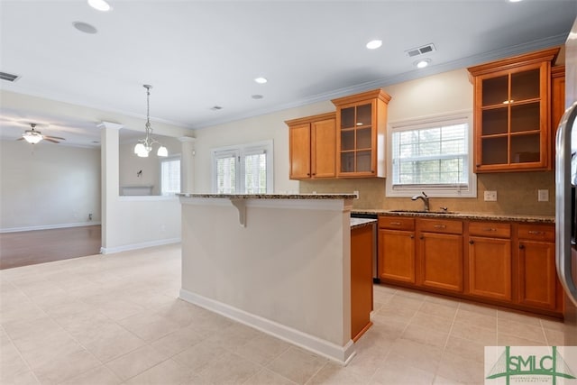 kitchen featuring ornamental molding, ceiling fan with notable chandelier, backsplash, and light stone countertops