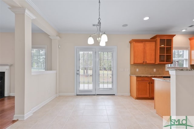 kitchen with a chandelier, a healthy amount of sunlight, light stone counters, and ornamental molding