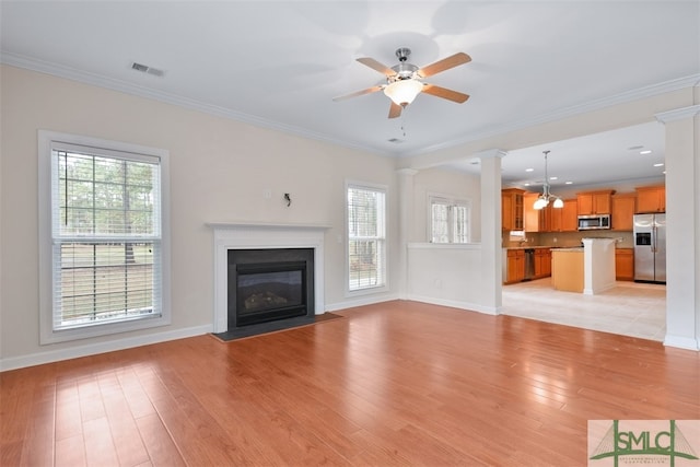 unfurnished living room featuring ceiling fan, ornate columns, light wood-type flooring, and crown molding