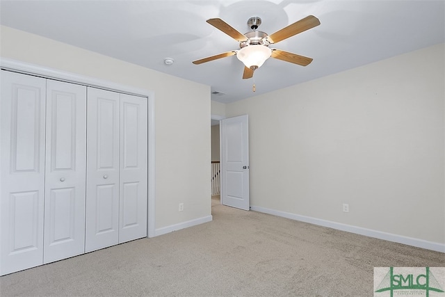 unfurnished bedroom with light colored carpet, ceiling fan, and a closet