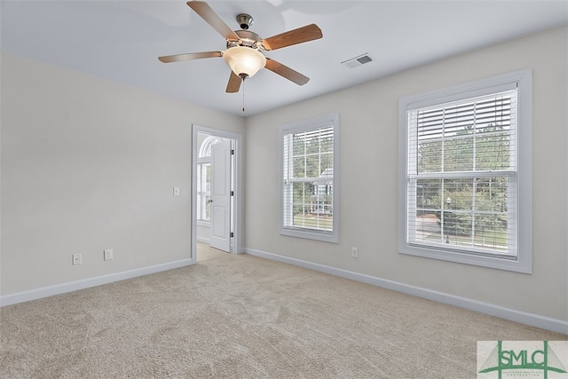 carpeted spare room featuring a wealth of natural light and ceiling fan