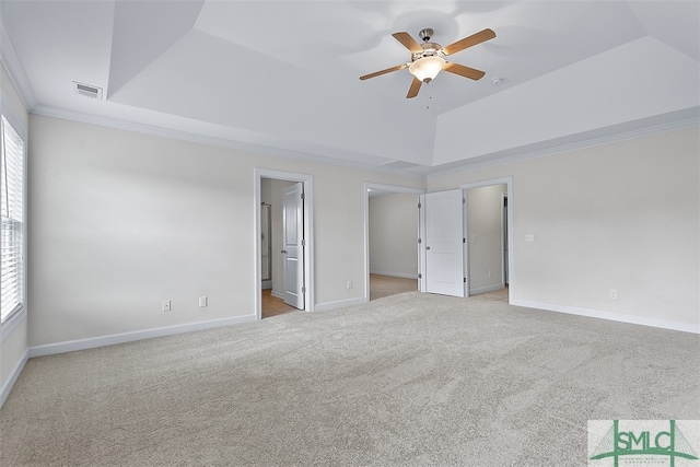 unfurnished bedroom with ensuite bath, light carpet, ceiling fan, a raised ceiling, and crown molding