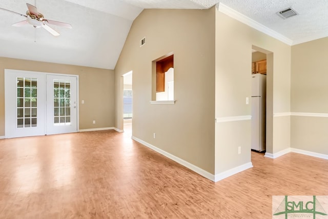 empty room with light wood-type flooring, lofted ceiling, a textured ceiling, and ceiling fan