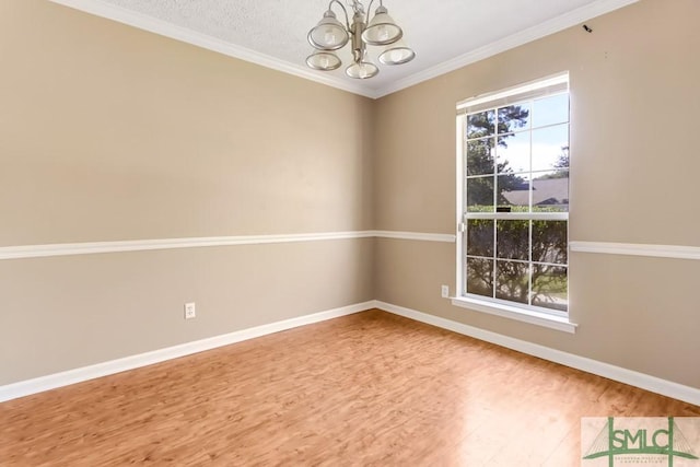 empty room featuring a textured ceiling, wood finished floors, baseboards, an inviting chandelier, and crown molding