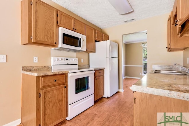 kitchen with white appliances, visible vents, light countertops, a textured ceiling, and a sink