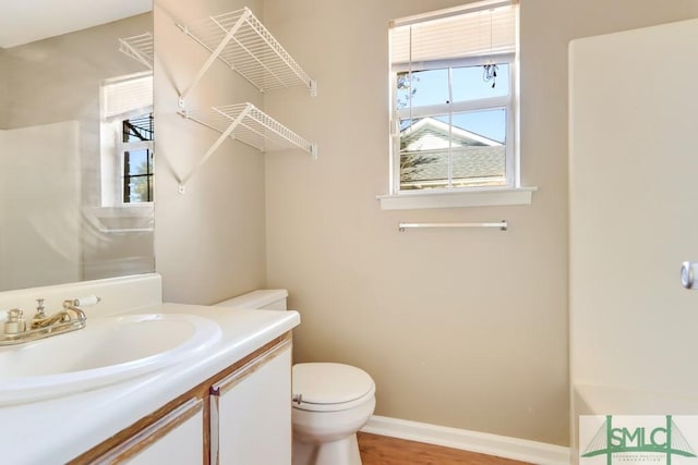 bathroom with toilet, baseboards, wood finished floors, and vanity