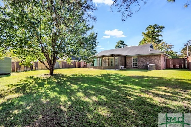 view of yard featuring a sunroom, a fenced backyard, and central AC unit