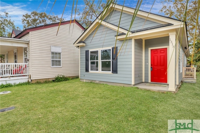 rear view of property featuring a porch and a yard