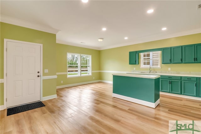 kitchen featuring crown molding, sink, light hardwood / wood-style floors, a kitchen island, and green cabinets