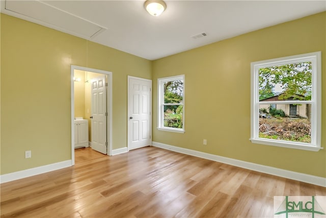 unfurnished bedroom with ensuite bath and light wood-type flooring