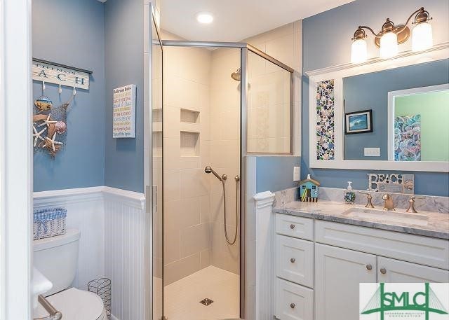 bathroom with a shower with shower door, vanity, and toilet