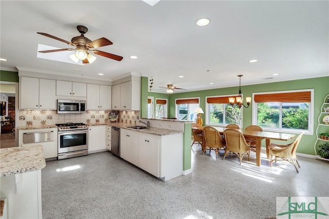 kitchen with pendant lighting, kitchen peninsula, appliances with stainless steel finishes, and white cabinetry