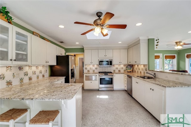 kitchen featuring a kitchen bar, kitchen peninsula, appliances with stainless steel finishes, and white cabinets