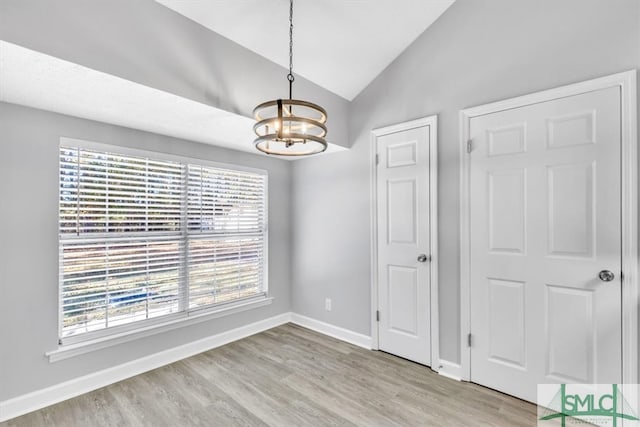 spare room with light hardwood / wood-style flooring, lofted ceiling, and a notable chandelier