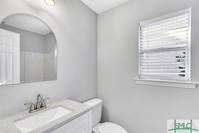 bathroom featuring toilet, vanity, and a textured ceiling