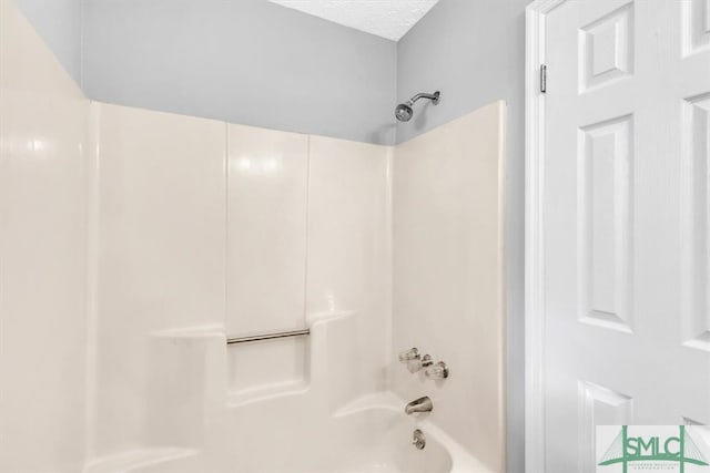 bathroom with shower / bathtub combination and a textured ceiling