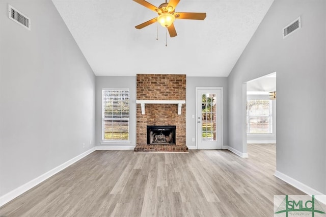 unfurnished living room featuring a textured ceiling, a fireplace, high vaulted ceiling, ceiling fan, and light wood-type flooring