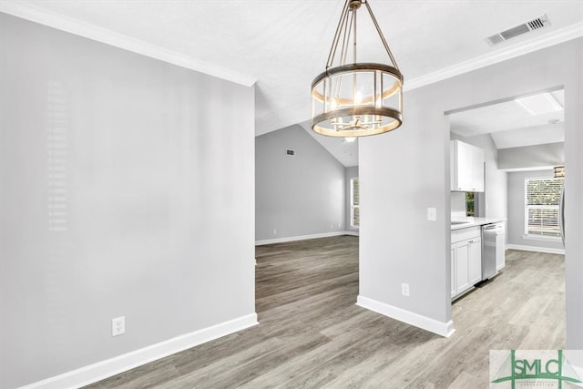 interior space with lofted ceiling, an inviting chandelier, light wood-type flooring, and crown molding