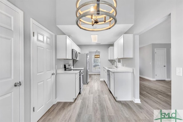 kitchen featuring a chandelier, white cabinets, light hardwood / wood-style floors, and stainless steel appliances