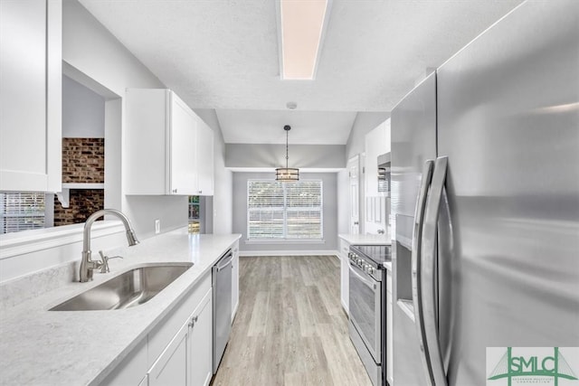 kitchen featuring decorative light fixtures, white cabinetry, appliances with stainless steel finishes, and sink