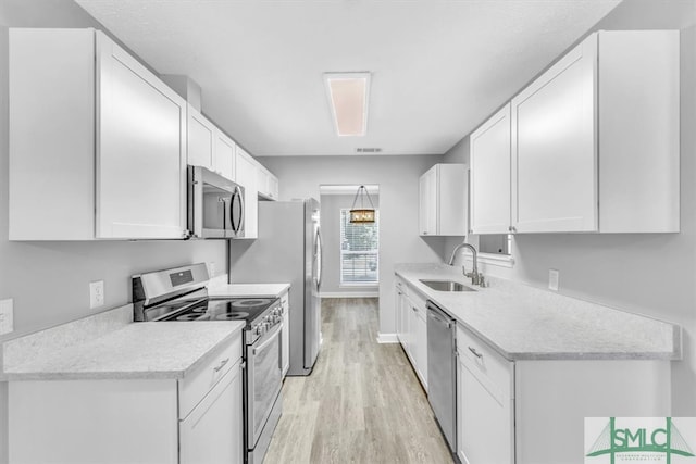 kitchen with light hardwood / wood-style floors, white cabinetry, sink, and appliances with stainless steel finishes