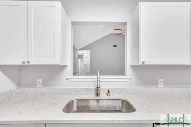 kitchen featuring white cabinets, sink, and light stone countertops