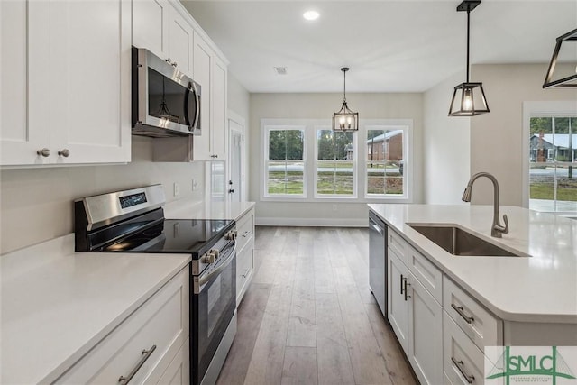 215 Wildwood Dr, Sylvania, GA 30467 - kitchen featuring stainless steel appliances, wood-type flooring, light countertops, white cabinets, and pendant lighting