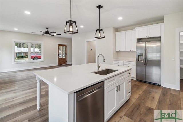 215 Wildwood Dr, Sylvania, GA 30467 - kitchen featuring stainless steel appliances, wood finished floors, a kitchen island with sink, light countertops, and decorative light fixtures