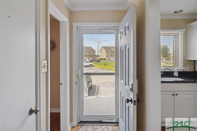 doorway featuring sink, light wood-type flooring, and crown molding