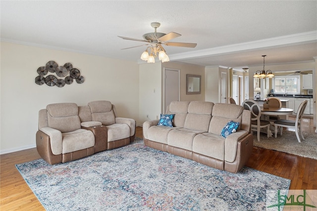 living room with ceiling fan with notable chandelier, dark hardwood / wood-style flooring, sink, and crown molding