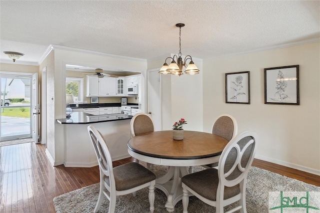 dining room with a textured ceiling, ornamental molding, and dark hardwood / wood-style floors