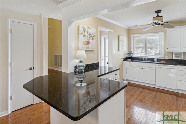 kitchen with dark wood-type flooring, white dishwasher, white cabinets, a textured ceiling, and crown molding