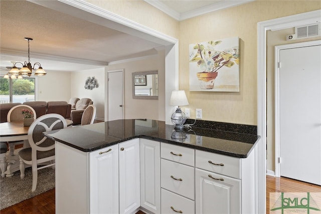 kitchen featuring dark stone counters, white cabinetry, dark hardwood / wood-style flooring, and crown molding