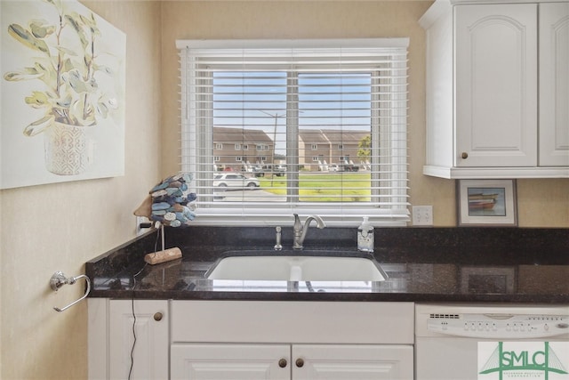 kitchen featuring white cabinets, dark stone counters, sink, and white dishwasher