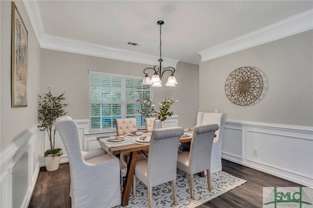 dining area featuring dark wood-type flooring, an inviting chandelier, and crown molding